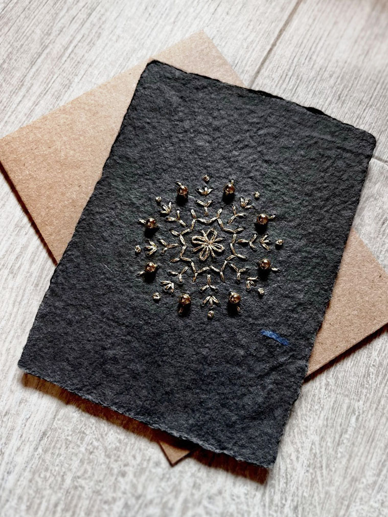 Gold-thread snowflake with beads on black handmade paper